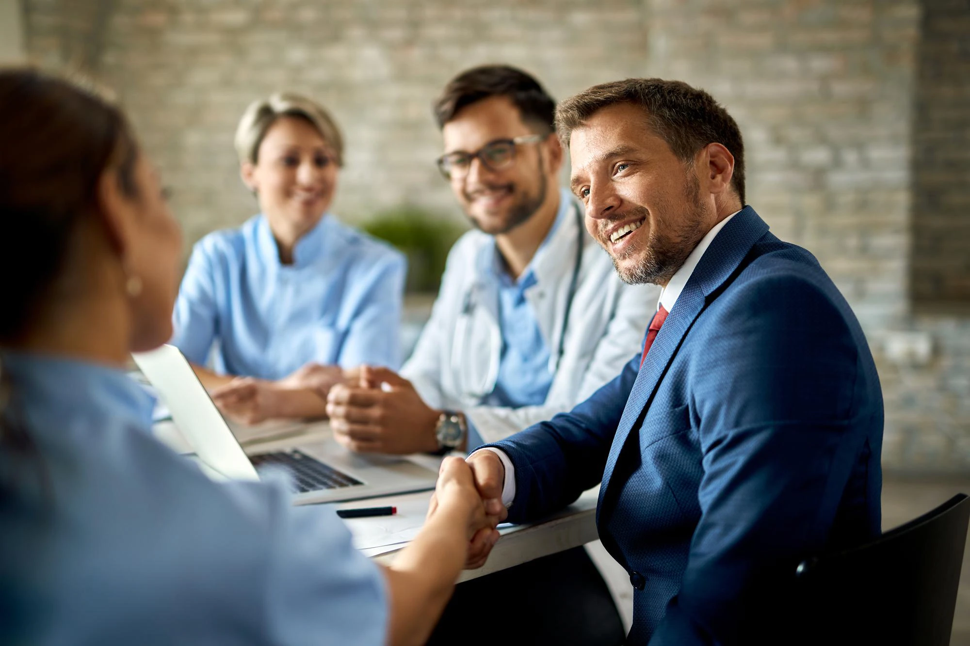 happy-businessman-having-meeting-with-group-doctors-shaking-hands-with-one-them-office_637285-7072